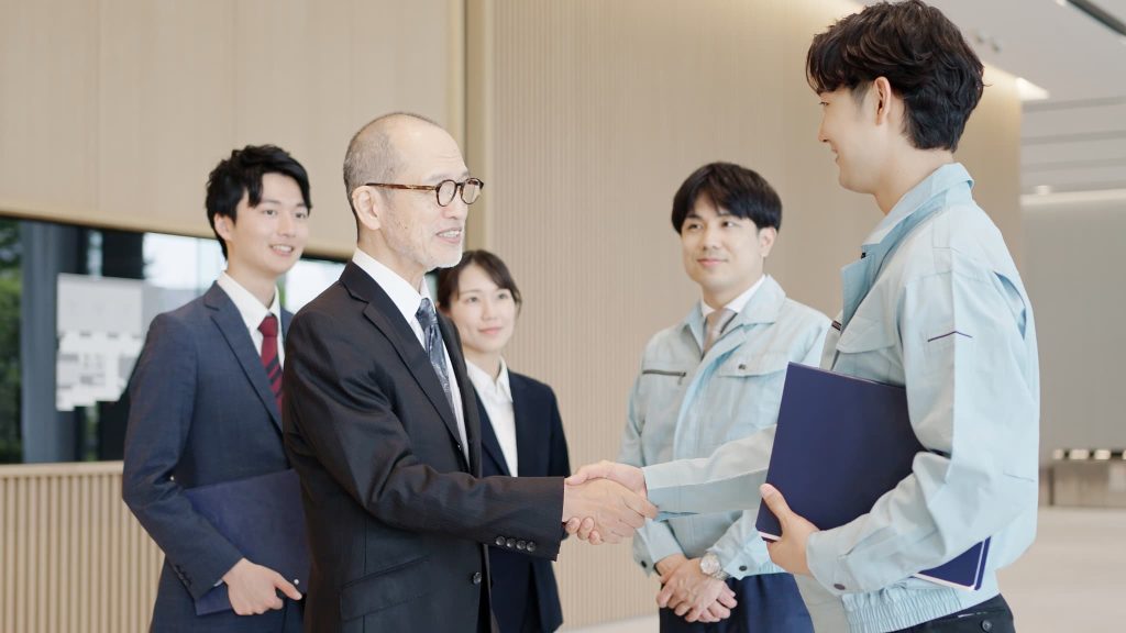 良好な営業キャッシュフローを背景に、新規取引や事業拡大に向けて笑顔で握手を交わす経営者と技術者