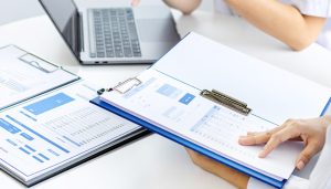 債権譲渡の一種であるファクタリングが法的に認められた手段であることを確認し、悪徳業者を避けるために手数料や契約内容について資料を用いながら入念に相談する様子