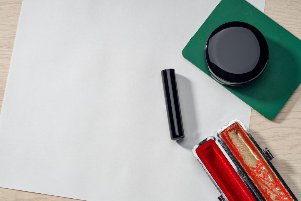 木目調のデスクに置かれた真っ白な紙と印鑑、印肉。新創業融資制度の実行に伴う金銭消費貸借契約など、重要な捺印手続きを象徴するイメージ