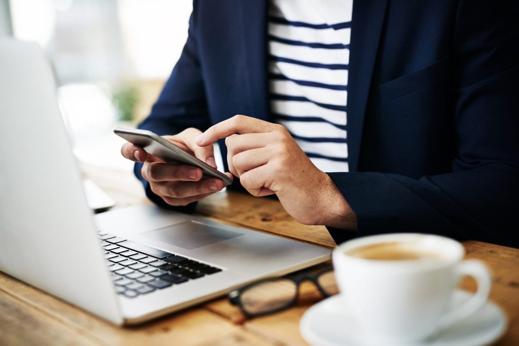 外出先で新規事業の最新情報をチェックしたり、補助金の公募状況をスマートフォンで確認したりするビジネスパーソン