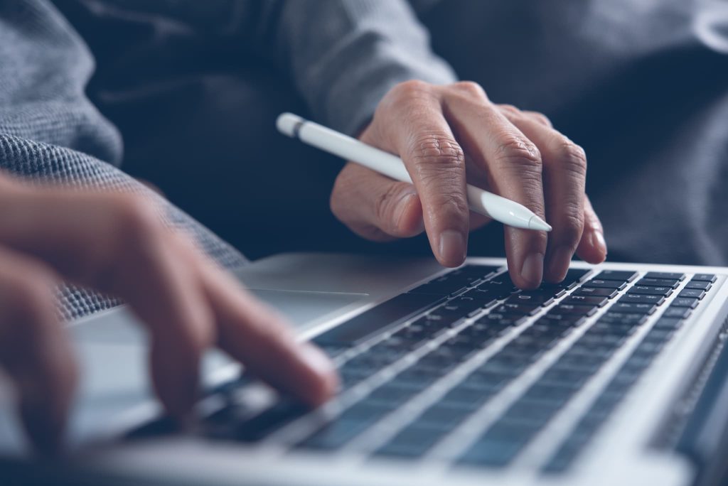 ノートパソコンのキーボードでタイピングするビジネスパーソンの手元。事業計画書を作成し、必要な開業資金の総額をシミュレーションしている様子