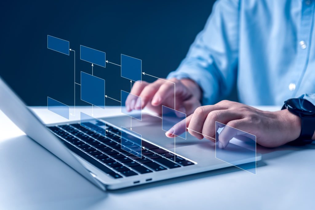 新規事業のビジネスモデルや補助金活用の工程を検討するために、ノートパソコンでフローチャートを操作する手元