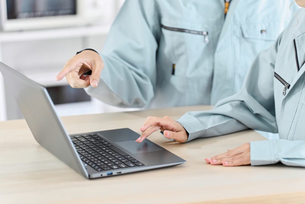 作業着を着た二人がノートパソコンの画面を指差して打ち合わせる様子。製造業や建設業での起業にあたり、新創業融資制度で設備資金を調達するイメージ