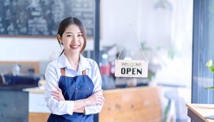 設備資金や運転資金などの開業資金を適切に調達し、綿密な資金計画をもとに念願の店舗をオープンさせた女性オーナーが笑顔で店内に立つ様子