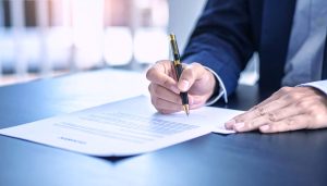 ファクタリングの必要書類である請求書や決算書を揃え、早期の資金調達を実現するために2社間ファクタリングの契約手続きをスムーズに進めるビジネスマンの手元