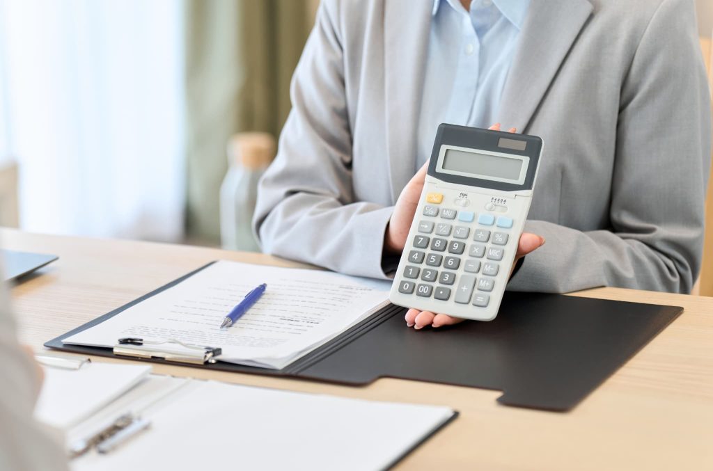 ファクタリングの手数料はやばいほど高額ではないと示すために電卓を相手に向けて提示している女性担当者