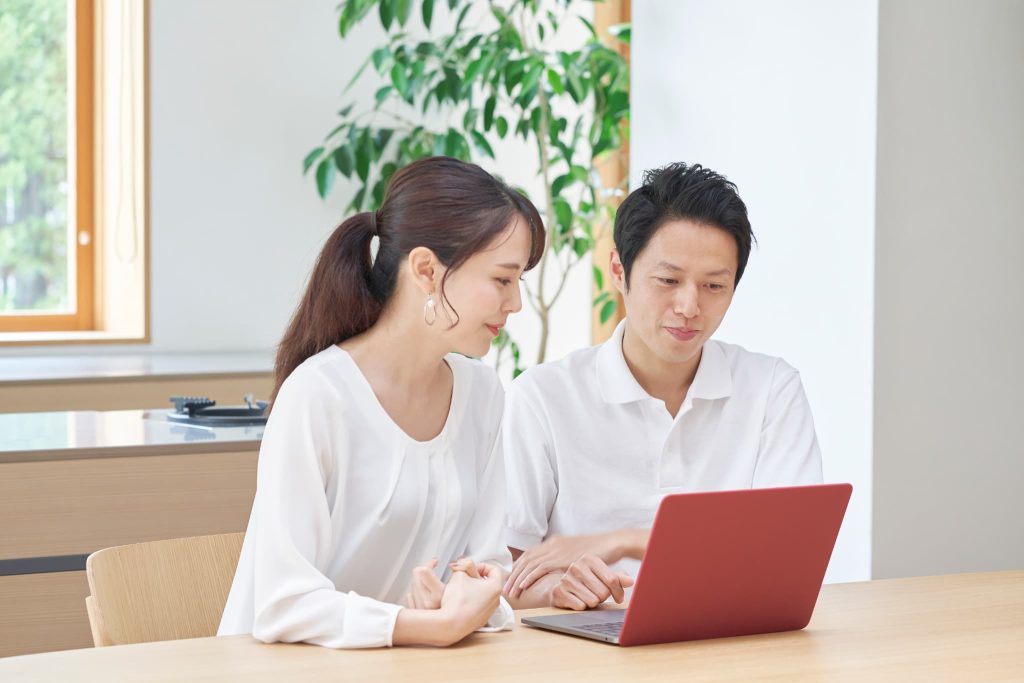 ファクタリングはやばいものではないか赤いパソコンの画面を一緒に見ながら真剣に相談している夫婦