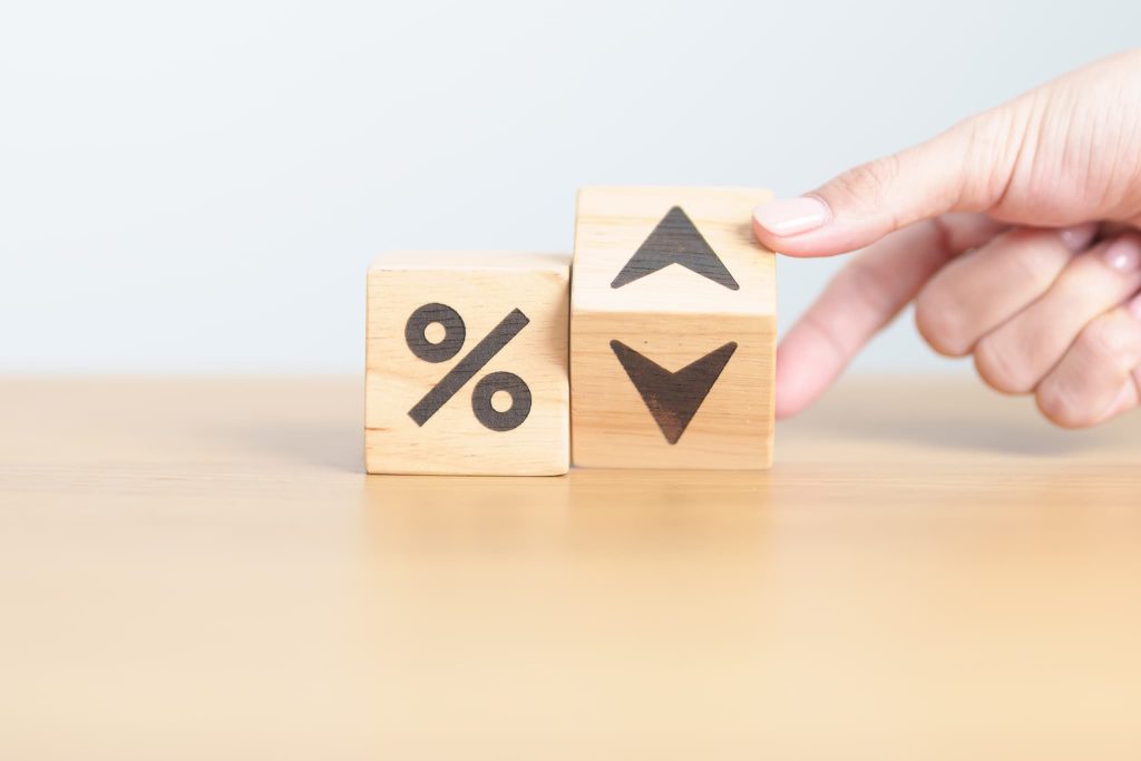 ％（パーセント）と矢印が描かれた積み木を動かす手元。ビジネスローンの金利変動や利率の比較を視覚的に表現