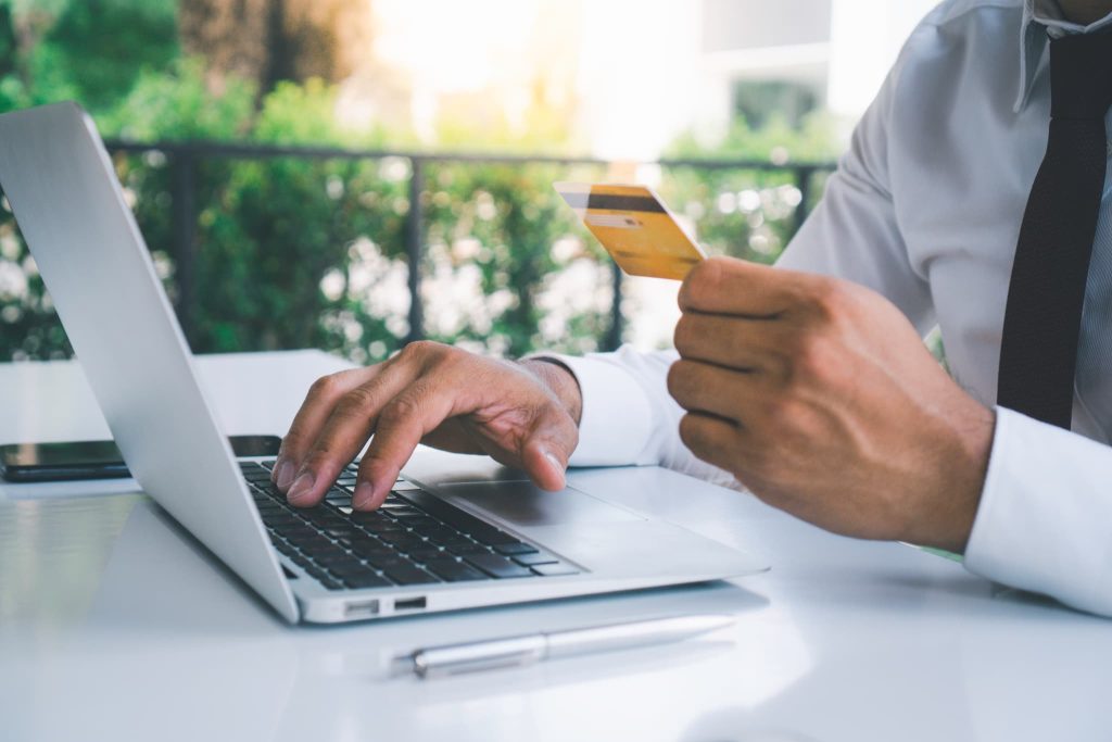 クレジットカードを手に持ちながらパソコンを操作する男性。ローン審査なしのカードローン申し込みやオンライン決済の手続きシーン
