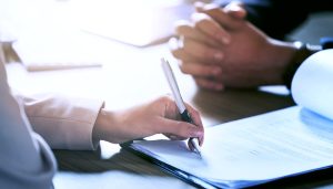 資金繰りの改善に向けて、保有する売掛債権を迅速に現金化できるファクタリングの契約書に署名し、スムーズな資金調達の実行を決定する様子