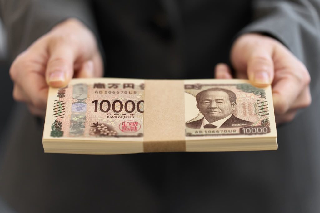 手渡される帯封のついた一万円札の札束。売掛債権を早期に現金化するファクタリングを活用し、迅速に資金調達が完了した様子を象徴するイメージ