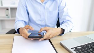 日本政策金融公庫や銀行から運転資金の融資を受けるため、スマホで返済計画を立てたり書類準備不要な資金調達サービスを検討したりする個人事業主の様子