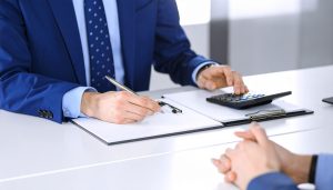 数万円規模の少額な売掛債権でも対応可能なファクタリング会社において、資金不足を解消するための審査通過のポイントや手数料を電卓でシミュレーションしながら相談する様子