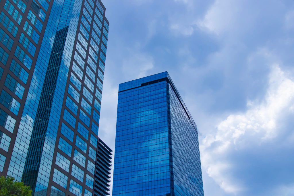 青空の下にそびえ立つ近代的なオフィスビル群。個人事業主が銀行や日本政策金融公庫などの金融機関から運転資金の融資を受けるビジネス環境を象徴