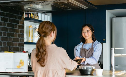 アルバイトの雇用の流れを説明する記事のメイン画像。女性のアルバイトスタッフが飲食店のカウンターでキャッシュレス決済をしている。