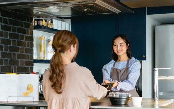 アルバイトの雇用の流れを説明する記事のメイン画像。女性のアルバイトスタッフが飲食店のカウンターでキャッシュレス決済をしている。