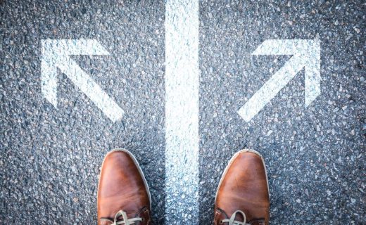 開業を決意するまでのステップを解説する記事のメイン画像。左右に分かれた矢印の前に立つ足元で、人生の岐路や開業への迷い、そして決断の瞬間を象徴的に表現