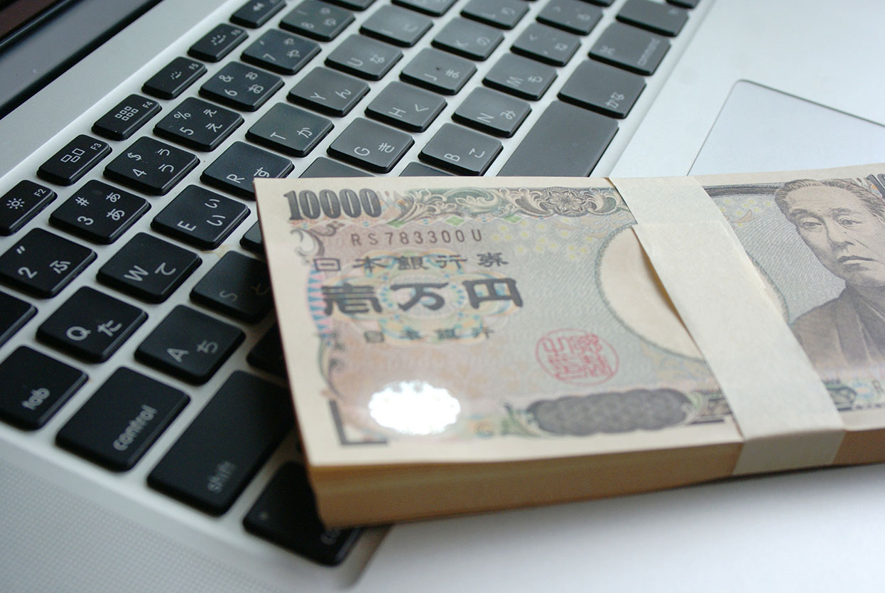 開業資金イメージ（ノートパソコンと一万円札の札束）