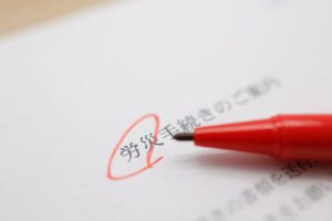 労災手続きのご案内書類に赤ペンで丸をつけている写真