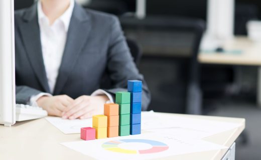 リスティング広告のインハウス化による成果改善をイメージした画像。デスクの上で、カラフルな積み木が右肩上がりのグラフを形作っている