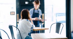 飲食店のオペレーション改善について解説する記事のメイン画像。笑顔の女性スタッフが接客している様子