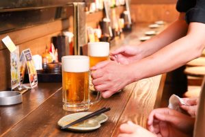 居酒屋のカウンターでビールを提供しているイメージ