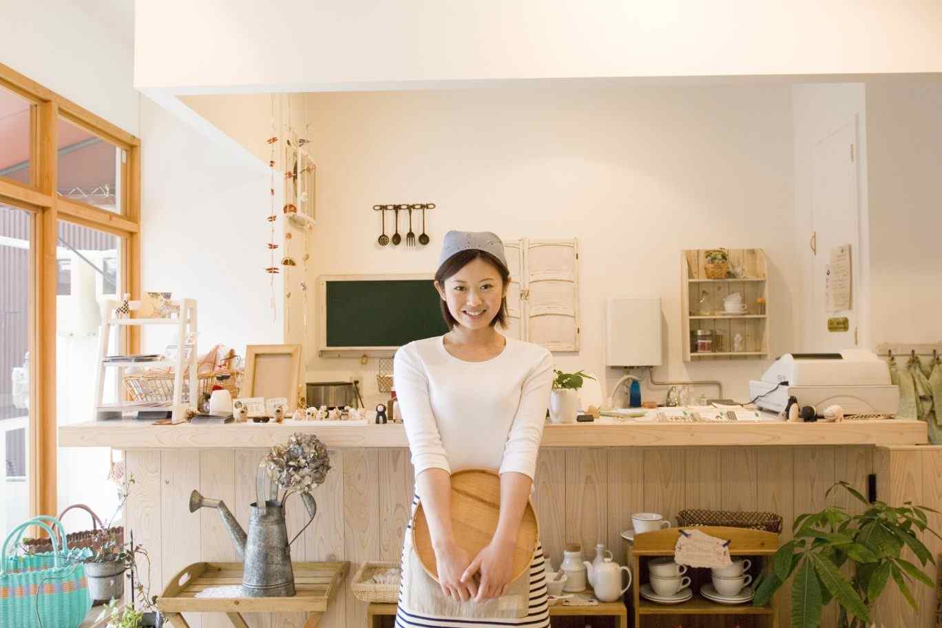 未経験からカフェを開業する方を応援するイメージ写真。エプロン姿の女性オーナーが自身の店で笑顔を浮かべており、夢を実現した姿を表現