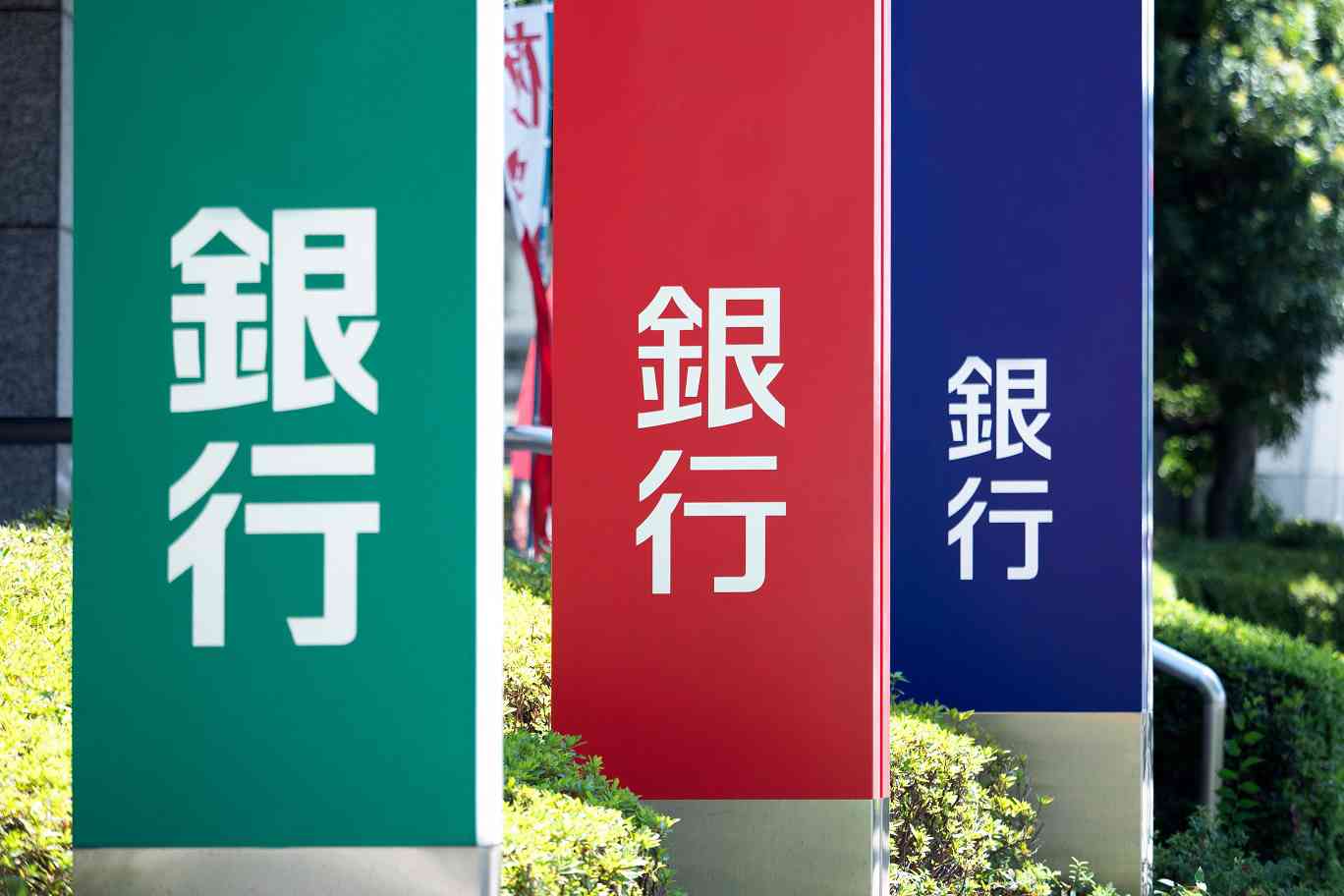 個人事業主におすすめの銀行口座を種類別に比較し紹介する章のイメージ写真。色が違う3つの「銀行」の看板で、メガバンク・ネット銀行・信用金庫など、さまざまな銀行の種類を表現