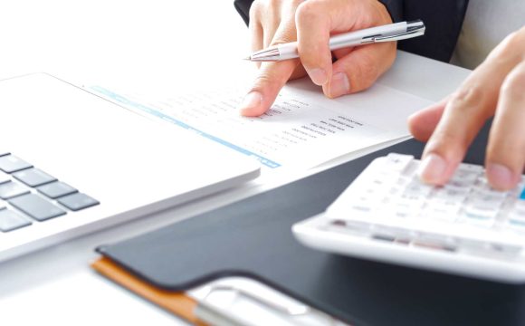 売上管理の目的と重要性を解説する記事のメイン画像。書類の数字を確認しながら電卓を使い、売上確認を行っている様子