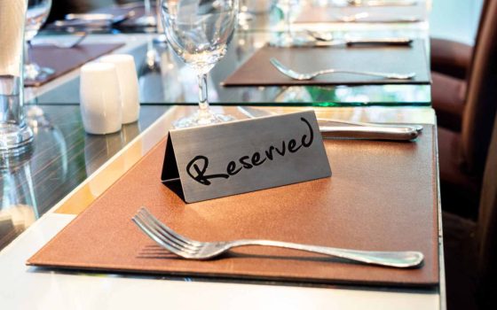 予約の無断キャンセル（ノーショー）防止策を解説する記事のメイン画像。レストランのテーブルに「Reserved」の札が置かれたまま、お客さまが来店していない様子