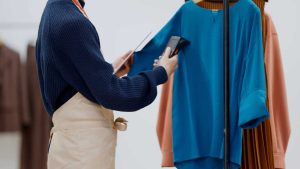 在庫管理の方法を解説する記事のメイン画像。アパレル店員がタブレットとバーコードリーダーを使い、洋服の在庫を管理している様子