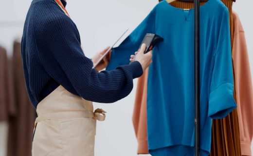 在庫管理の方法を解説する記事のメイン画像。アパレル店員がタブレットとバーコードリーダーを使い、洋服の在庫を管理している様子