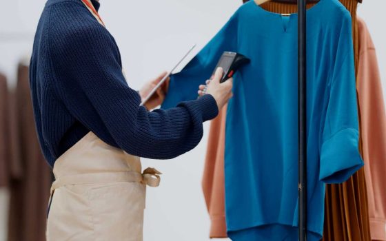 在庫管理の方法を解説する記事のメイン画像。アパレル店員がタブレットとバーコードリーダーを使い、洋服の在庫を管理している様子