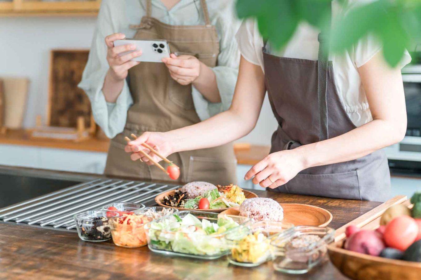 飲食店のメニュー開発の手順を解説する記事のメイン画像。エプロン姿のスタッフが、試作した料理の盛り付けを調整し、スマートフォンで記録・撮影している様子を表現
