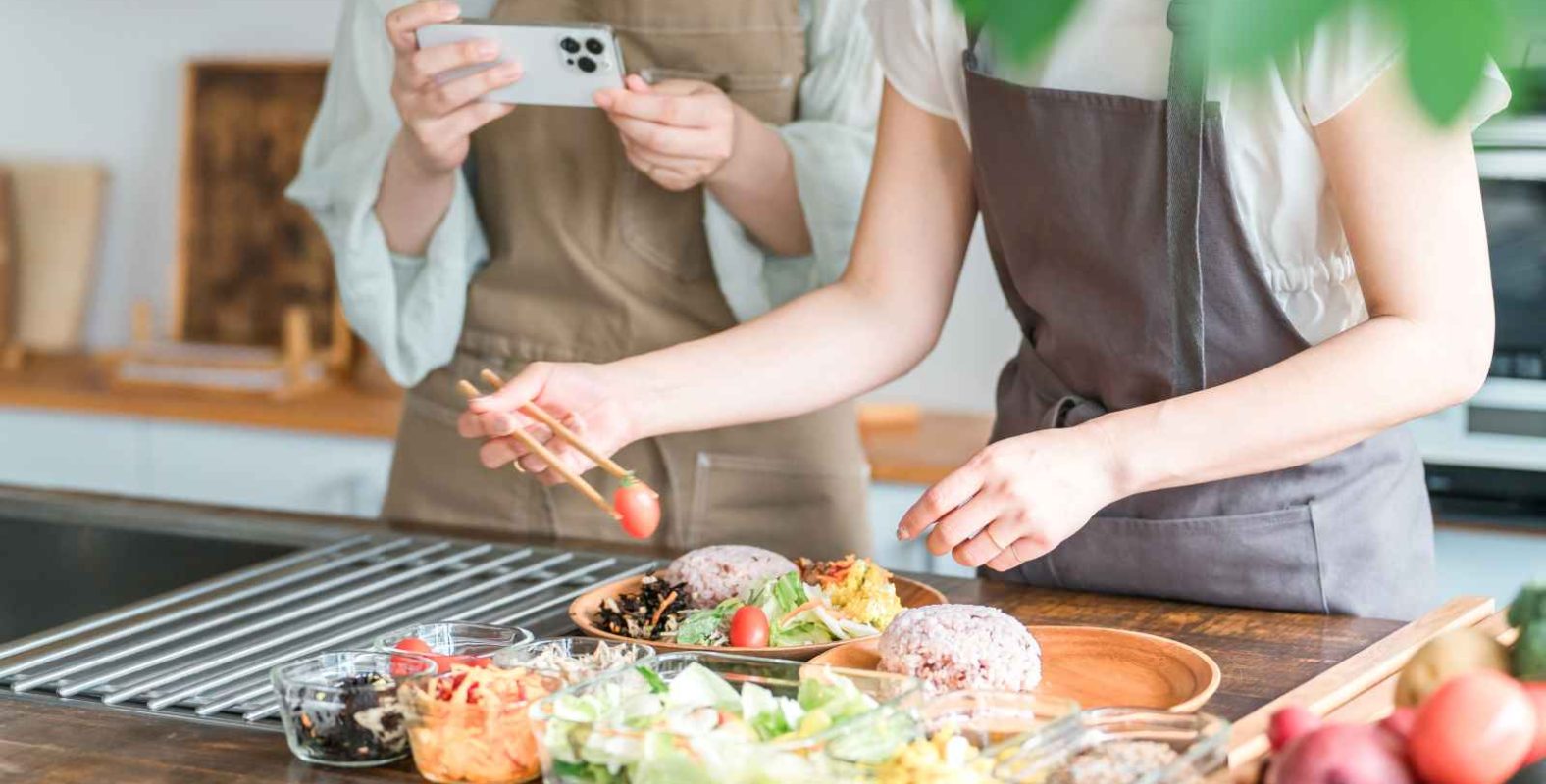 飲食店のメニュー開発の手順を解説する記事のメイン画像。エプロン姿のスタッフが、試作した料理の盛り付けを調整し、スマートフォンで記録・撮影している様子を表現