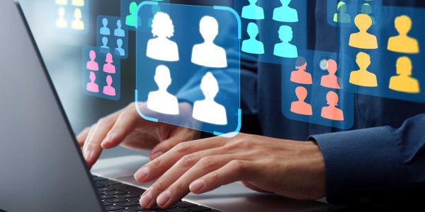 メイン写真：ノートパソコンを操作する手元に多数の人物アイコンが浮かび上がっている