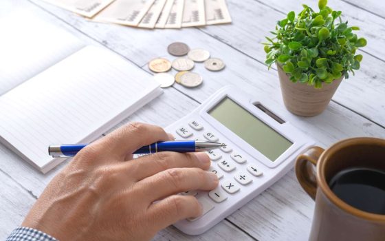 記事のメイン画像：テーブルの上に置いてある電卓で開業資金を計算している様子