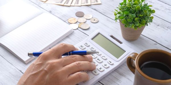 記事のメイン画像：テーブルの上に置いてある電卓で開業資金を計算している様子