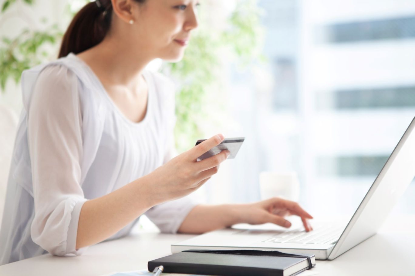 記事のメイン画像：開業届をe-Taxで提出しようとしている女性。手元にはパソコンとカードがある