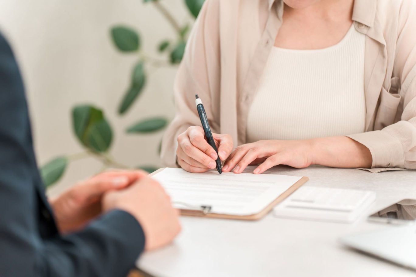 記事のメイン画像：ベージュの服を着た女性が、税理士指導のもと開業届用紙に店舗情報を記入している