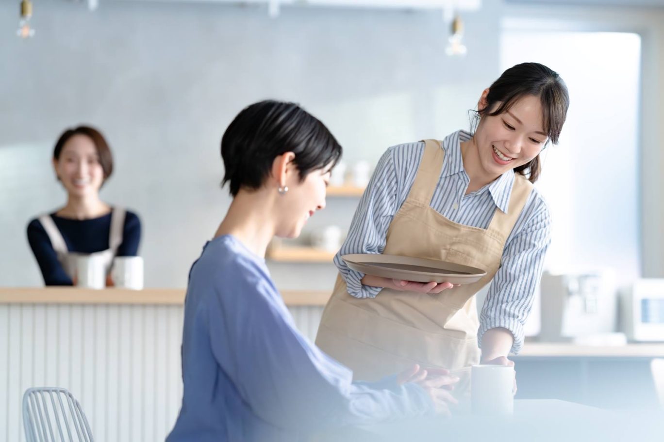 記事のメイン画像：エプロン姿のスタッフが笑顔で接客している。ルールや行動指針が整うことでスタッフが迷わず働けている様子