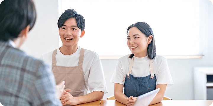 写真：専任スタッフと会話する2名の店舗スタッフ